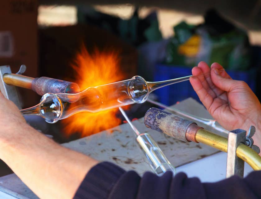 Um soprador de vidro queimando um pedaço de vidro em uma empresa de vidro soprado.