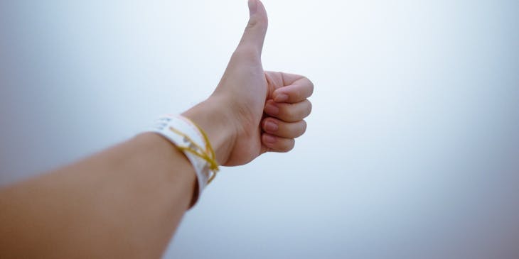 Person extending their arm while showing a thumbs up sign.