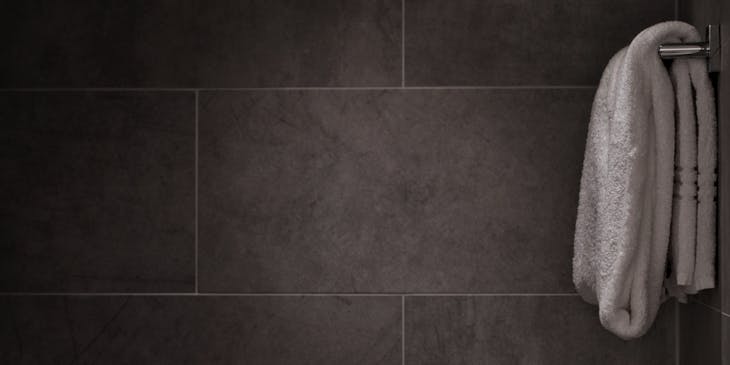 A towel rack against dark slate tiles with white grout.