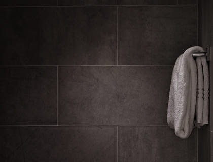 A towel rack against dark slate tiles with white grout.
