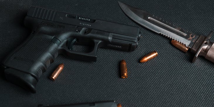 Gun with ejected magazine and bullets on a black background.