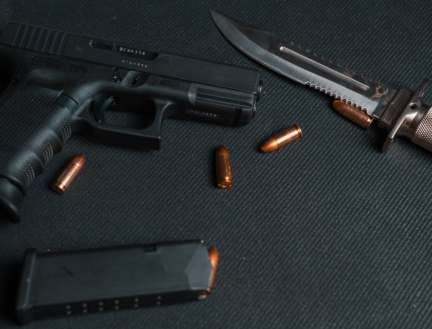 Eine Pistole liegt neben einem Magazin und Munition in einem Waffengeschäft neben einen Messer.