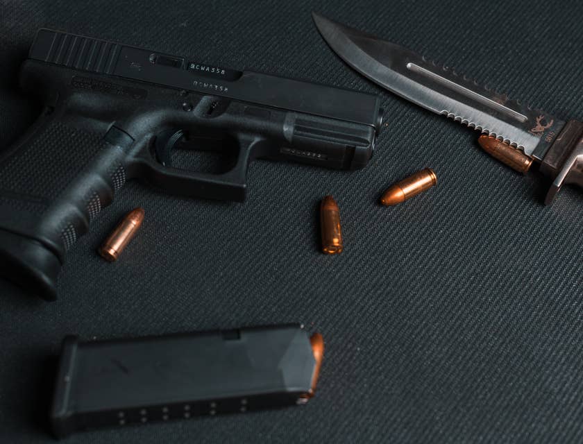 Eine Pistole liegt neben einem Magazin und Munition in einem Waffengeschäft neben einen Messer.