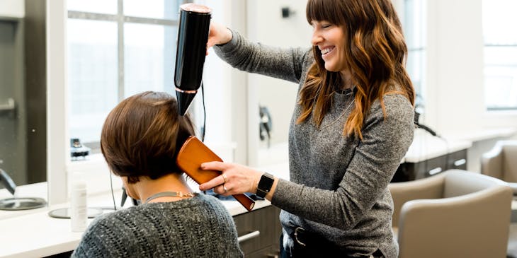 Hairdresser blowdrying a woman's hair.