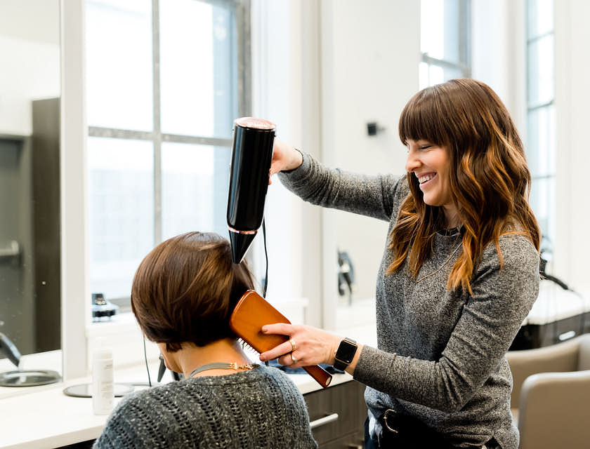 Una hair & makeup artist che fa la piega a una cliente.