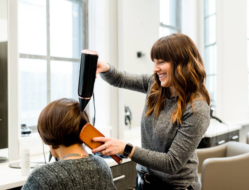 Une coiffeuse qui sèche les cheveux d'une femme dans une entreprise de coiffure et de de maquillage..