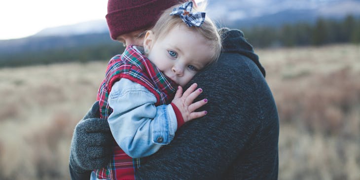 baby wearing a blue bow held by her dad
