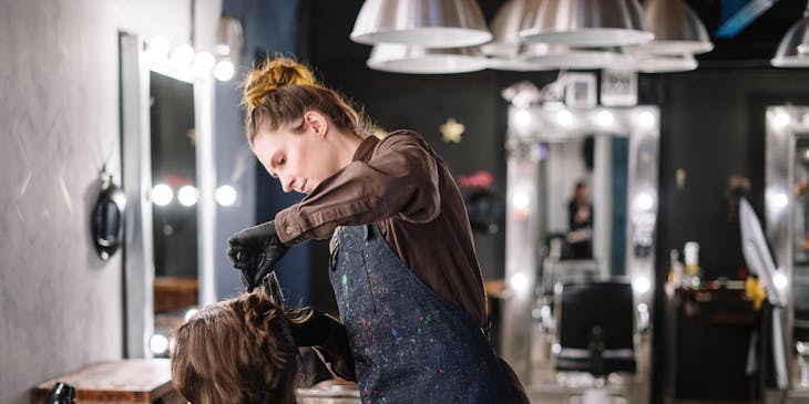 A hairstylist working at a hair business and cutting a customer's hair.