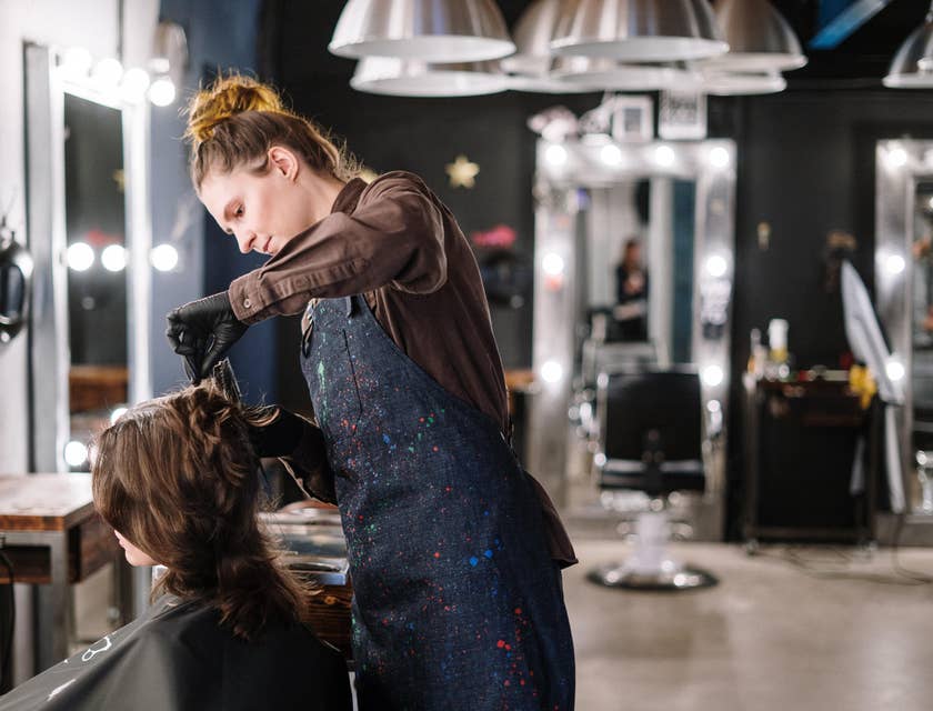 Eine Friseurin schneidet und färbt die Haare einer Kundin in ihrem Salon.