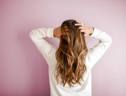 Uma mulher passando os dedos pelo cabelo após usar produtos para cabelo.