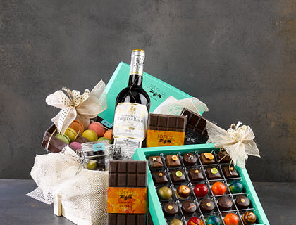 A hamper filled with chocolate, wine, and other items.