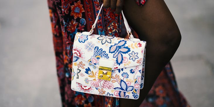 A person holding a white handbag purchased from a handbag business.