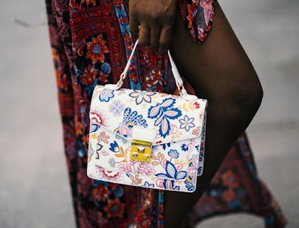A person holding a white handbag purchased from a handbag business.