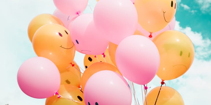 Pink and yellow balloons with smiles on them.