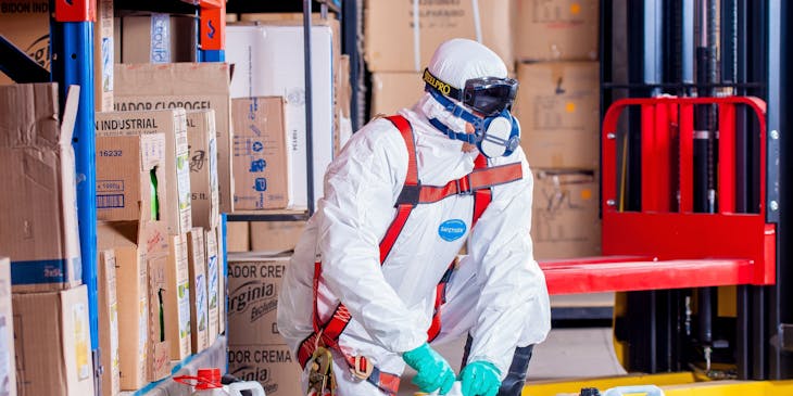 Man in hazmat suit disposing of hazardous waste.