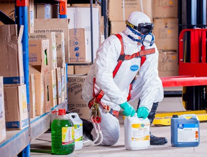 Man in hazmat suit disposing of hazardous waste.