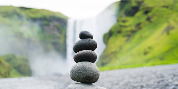 Rocks of varying sizes stacked on top of each other on the beach, representing health and wellness.