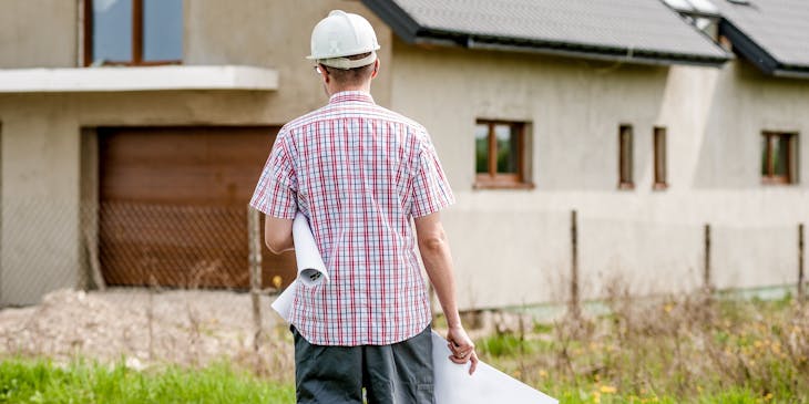Architect walking towards newly built home.