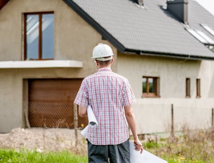 Un promoteur immobilier marchant vers une maison nouvellement construite.