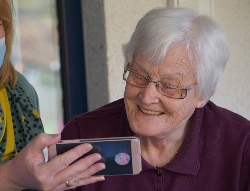Infirmière tenant un téléphone portable pour qu'une femme âgée puisse voir l'écran dans une maison de retraite.