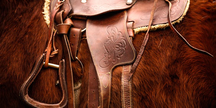 Close up of saddle on chestnut horse.