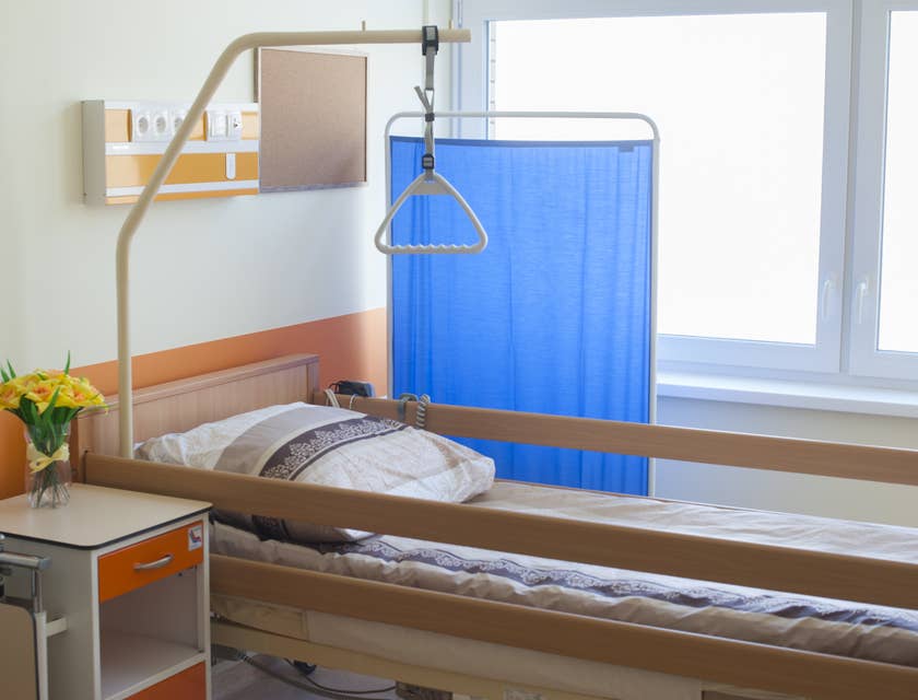 Uma cama ao lado de uma cortina azul em um quarto de hospício.
