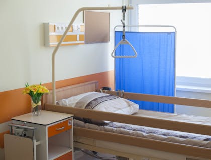 Un lit avec rembardes situé à côté d'un écran bleu dans un centre de soins palliatifs.