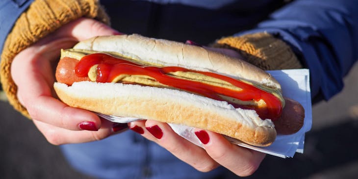 Mains d'une cliente avec un hot-dog.