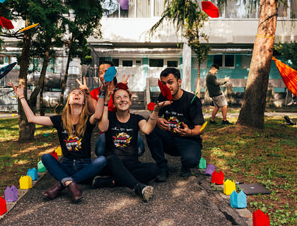 three young people at a charity party sitting on the ground