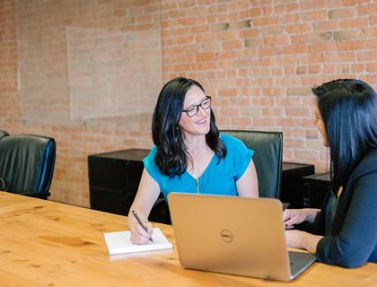 two women talking in front of computer