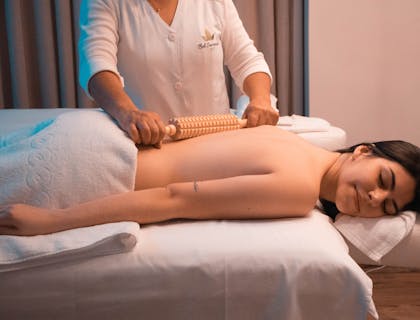 Una mujer acostada recibiendo masaje con rodillo de madera en un Day Spa.