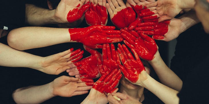 Muchas manos juntas con un corazón rojo pintado en ellas en una fundación.