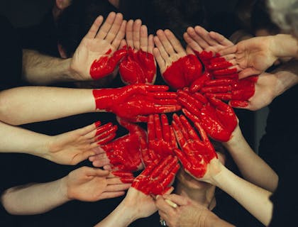 many hands together with red heart painted on them