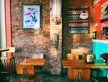 Empty tables in front of a face brick wall.