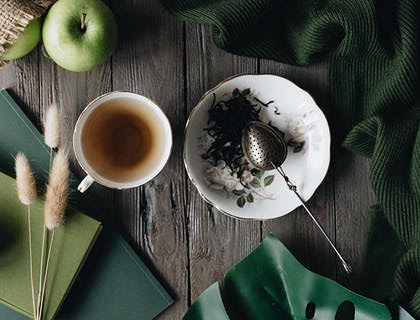White teacup on a wooden table with a tea strainer next to it.