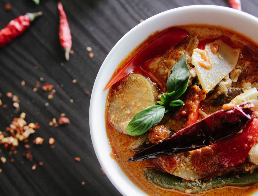 bowl of red curry soup with hot pepper and basil leaf