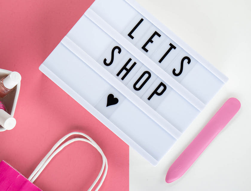Un cartel junto al esmalte de uñas sobre un fondo rosa y blanco.