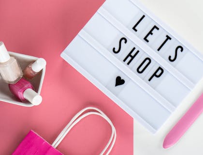 a sign next to nail polish on a pink and white background