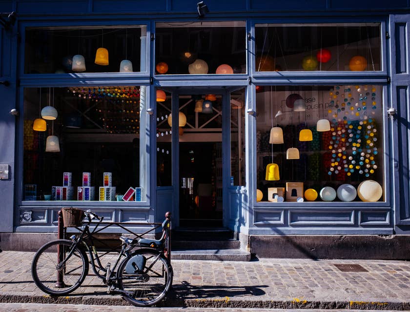 Storefront with lights in the window and a bicycle in the street.