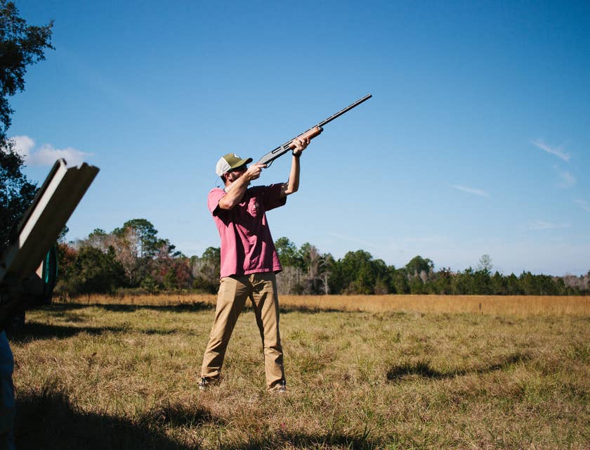 Un uomo che prende la mira con un fucile in un campo aperto per la caccia.