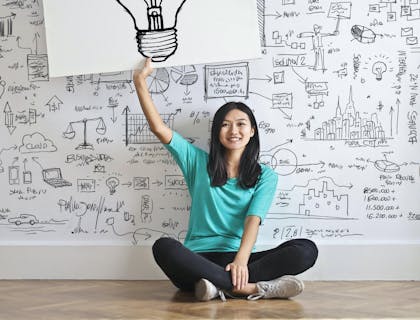 Mão segurando um marcador branco e escrevendo palavras "inovação" e "ideias" em inglês
