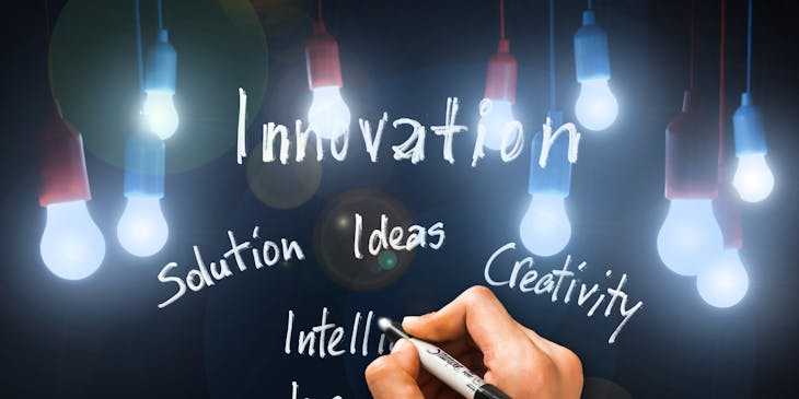 Hand holding white marker beneath the words 'innovation' and 'ideas'.