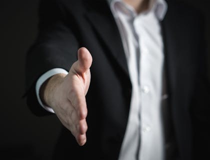 Un hombre de traje con la mano extendida para dar un apretón de manos en una compañía de seguros.