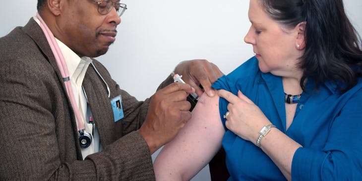 Male clinician injecting a patient's upper arm.