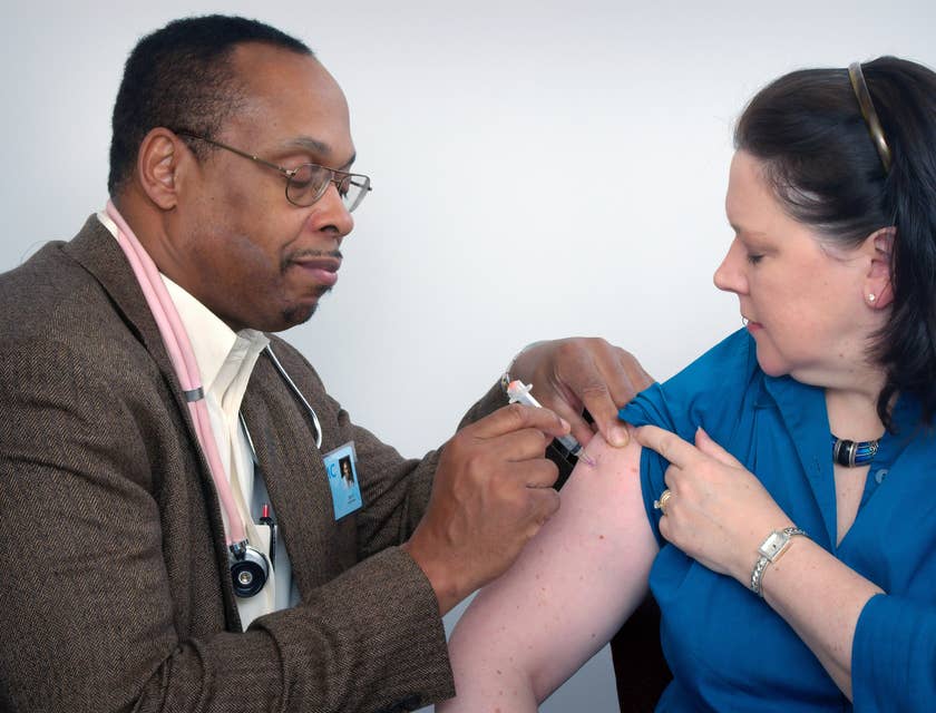 Male clinician injecting a patient's upper arm.