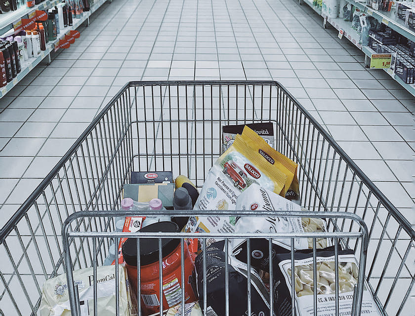 Carrinho de compras com vários alimentos e produtos importados em uma loja.