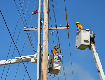 Un instalador de líneas de servicios de Internet poniendo cables de Internet en un poste de electricidad.