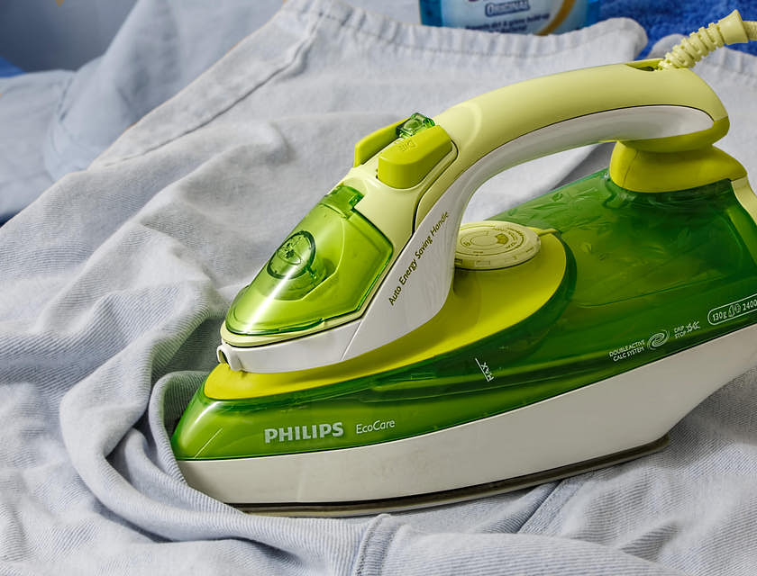 Una plancha de vapor blanca y verde neón, sobre una prenda blanca en un negocio de planchado.