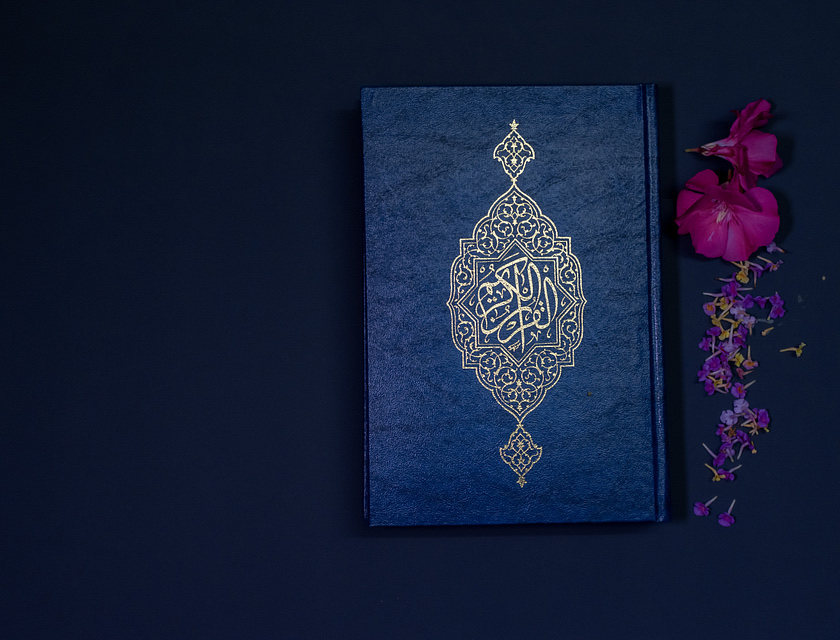 Le Coran et des fleurs sur un fond sombre.