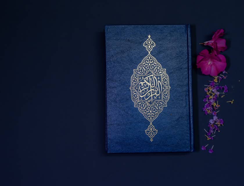 Le Coran et des fleurs sur un fond sombre.